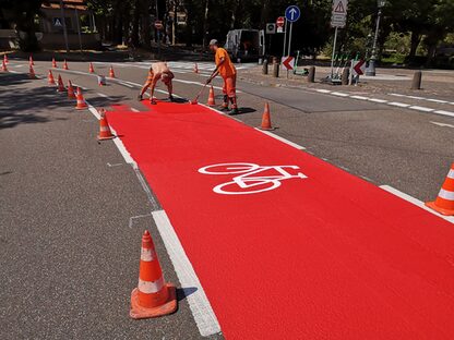 zwei Arbeiter markieren einen breite Radspur in leuchtendem Signalrot