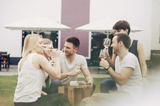 Junge Menschen sitzen im Garten und trinken Wein