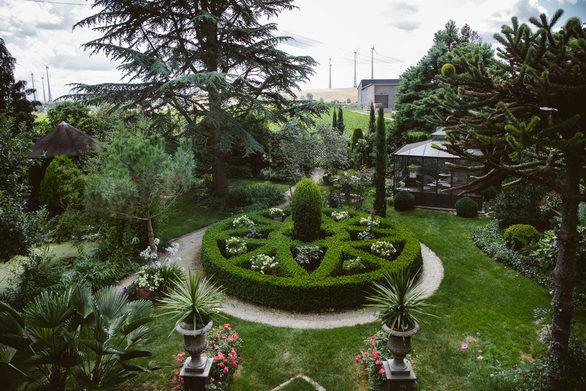 Garten im Weingut Listmann: Die himmelhohen Zypressen wecken sofort Erinnerungen an Italien, Palmen wachsen hinter dem Haus, und die Buchshecken formen labyrinthartig-verschlungene Formen.